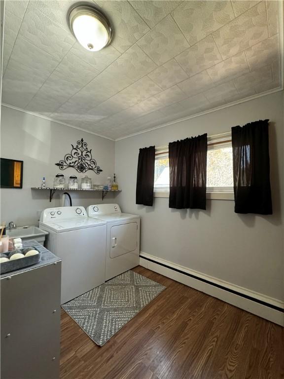 laundry area with baseboard heating, washing machine and clothes dryer, dark hardwood / wood-style flooring, and sink