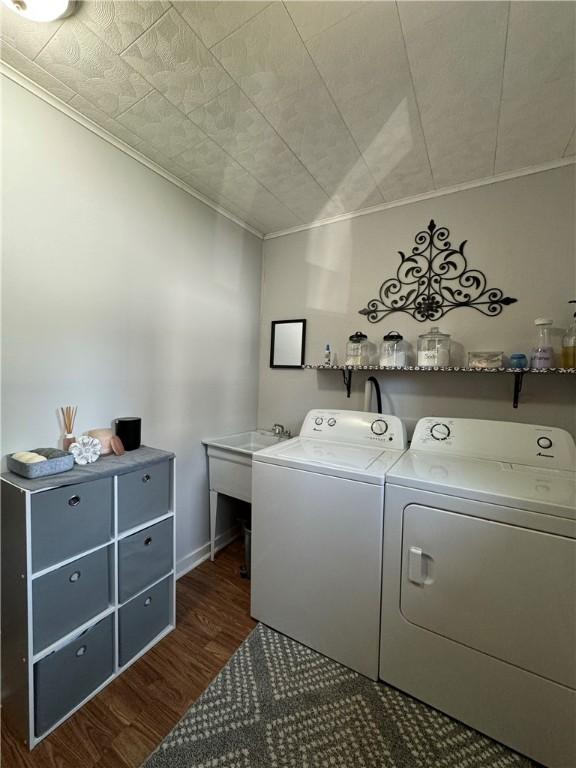 washroom with crown molding, washer and dryer, and dark hardwood / wood-style floors