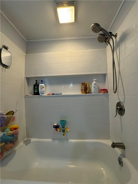 bathroom with tiled shower / bath combo and crown molding