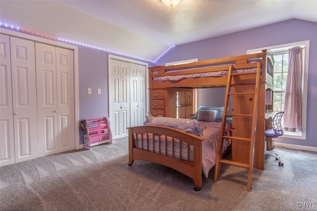 bedroom featuring carpet, two closets, and lofted ceiling