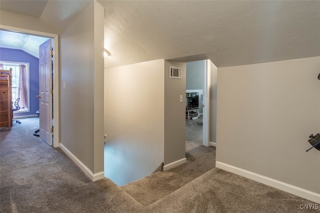 corridor with carpet, a textured ceiling, and lofted ceiling