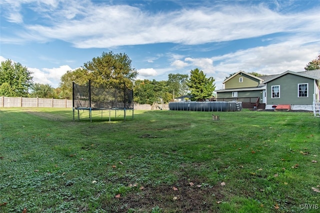 view of yard with a trampoline and a pool