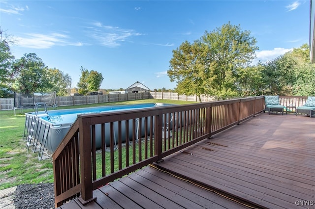 wooden terrace with a lawn, a fenced in pool, and a trampoline