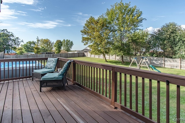 wooden terrace with a lawn, a playground, and a fenced in pool