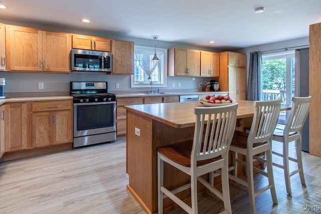 kitchen featuring decorative light fixtures, light wood-type flooring, stainless steel appliances, and a healthy amount of sunlight