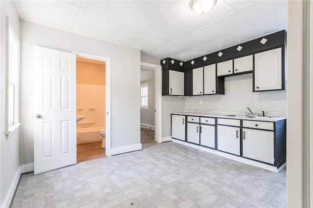 kitchen with white cabinets, a baseboard radiator, and sink