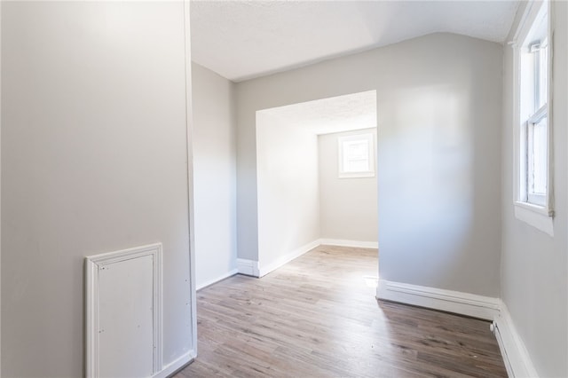 empty room featuring lofted ceiling, light hardwood / wood-style floors, and a textured ceiling