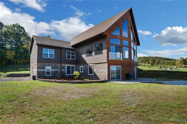 back of property featuring a balcony and a yard