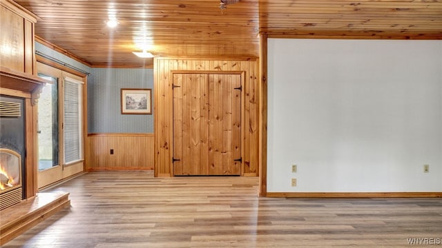 empty room featuring wooden ceiling, wooden walls, and light wood-type flooring