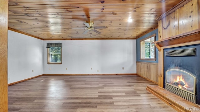 unfurnished living room with light wood-type flooring, wood ceiling, wood walls, and plenty of natural light