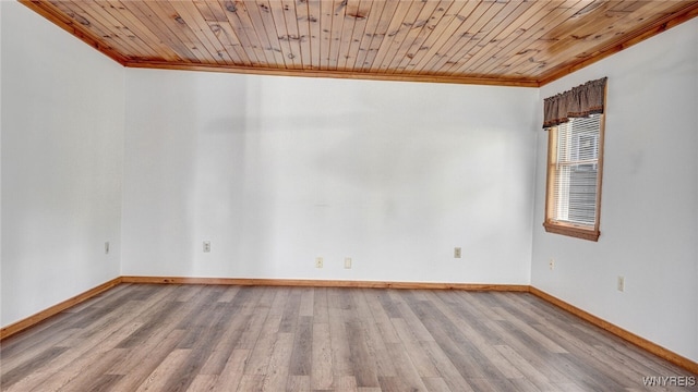 spare room featuring ornamental molding, light wood-type flooring, and wooden ceiling