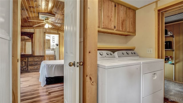 washroom featuring washing machine and dryer, light hardwood / wood-style floors, wooden ceiling, ceiling fan, and cabinets