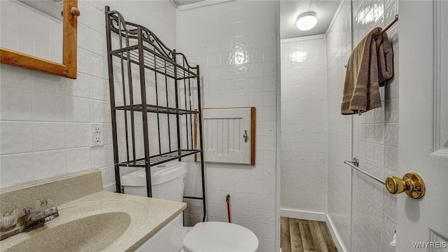 bathroom featuring tile walls, toilet, and wood-type flooring