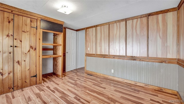 unfurnished bedroom with wooden walls and light wood-type flooring