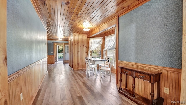 corridor featuring wooden ceiling, wooden walls, and light hardwood / wood-style flooring