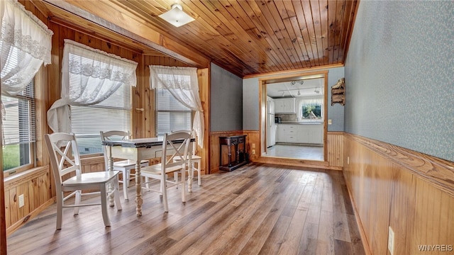 dining room featuring wood-type flooring, wood ceiling, and wooden walls