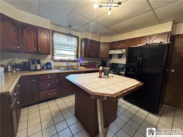 kitchen with dark brown cabinetry, sink, black appliances, a drop ceiling, and a center island