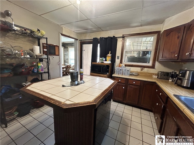 kitchen with light tile patterned flooring, tile countertops, plenty of natural light, and a center island