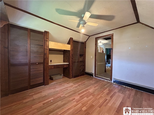 unfurnished bedroom with a baseboard heating unit, light hardwood / wood-style floors, a closet, vaulted ceiling, and ceiling fan