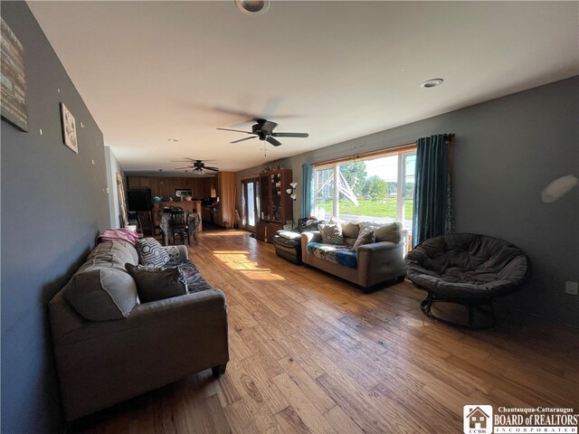 living room featuring light wood-type flooring, wooden walls, and ceiling fan