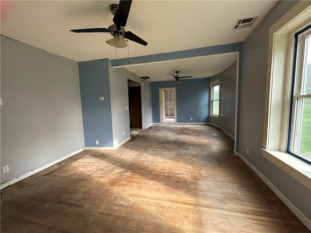 empty room with wood-type flooring, ceiling fan, and a healthy amount of sunlight