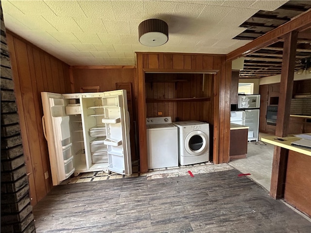 washroom with washing machine and clothes dryer, wooden walls, and hardwood / wood-style floors