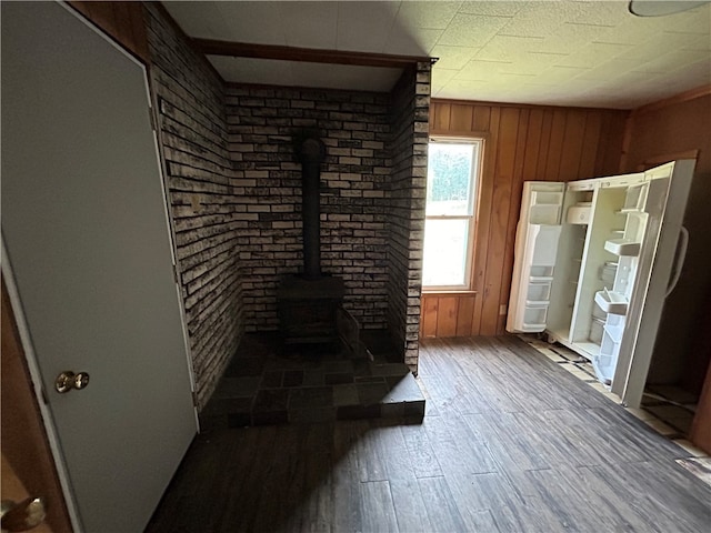 unfurnished living room with a wood stove, hardwood / wood-style flooring, and wooden walls