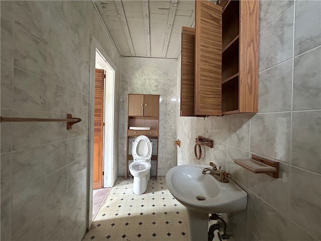 bathroom with tile walls, sink, and toilet