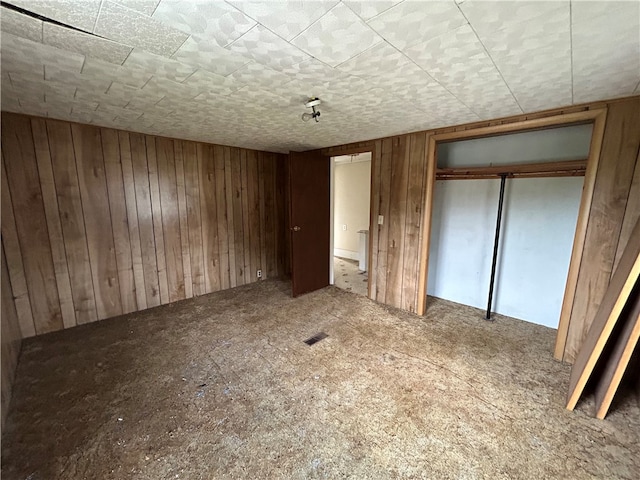 unfurnished bedroom featuring wooden walls and a closet