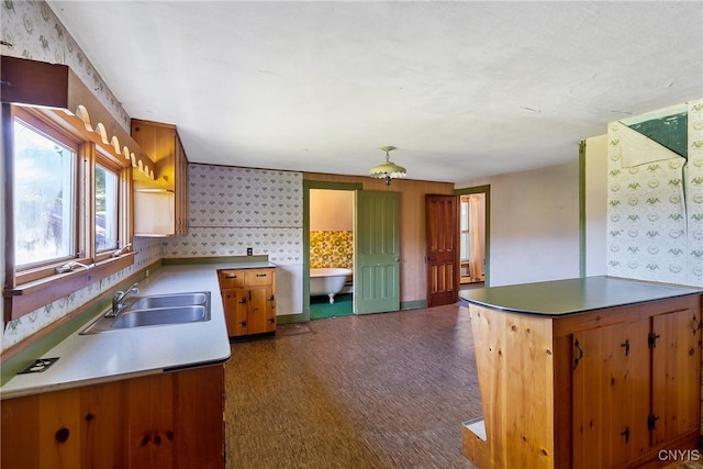 kitchen with kitchen peninsula, sink, and dark colored carpet