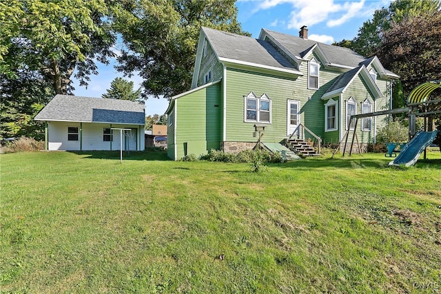 rear view of property with a playground and a yard