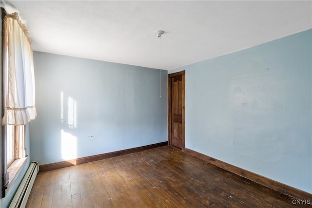 empty room featuring dark hardwood / wood-style floors and a baseboard heating unit