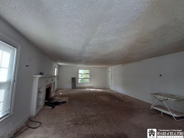 unfurnished living room featuring a textured ceiling and carpet flooring