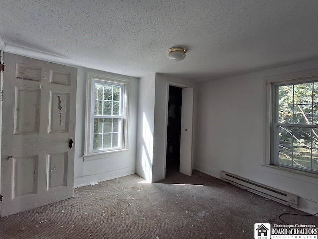 unfurnished bedroom with a baseboard heating unit, multiple windows, carpet floors, and a textured ceiling