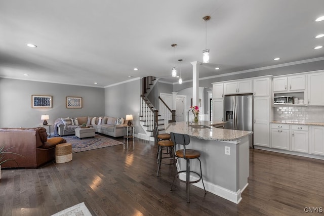 kitchen featuring hanging light fixtures, white cabinets, dark hardwood / wood-style flooring, light stone countertops, and sink