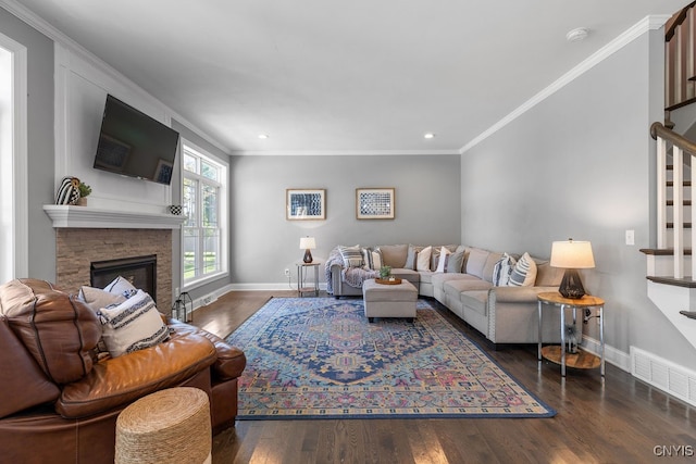 living room with crown molding, dark hardwood / wood-style floors, and a stone fireplace