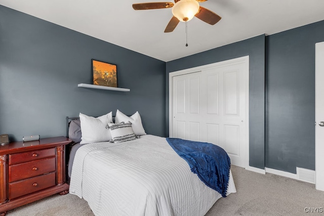 bedroom with ceiling fan, light colored carpet, and a closet