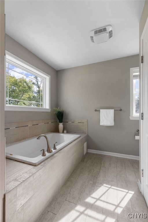 bathroom with tiled bath and hardwood / wood-style floors