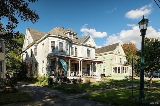 victorian-style house featuring a front lawn and covered porch