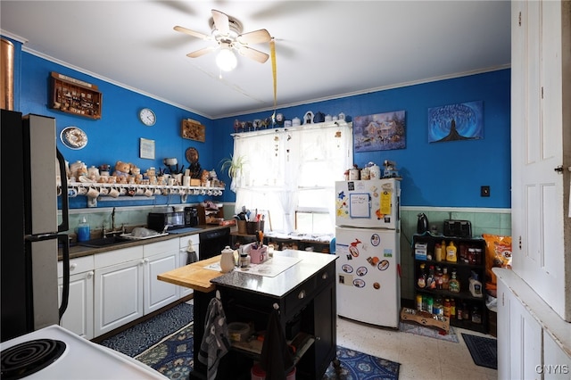 kitchen featuring white refrigerator, refrigerator, ceiling fan, black dishwasher, and white cabinetry