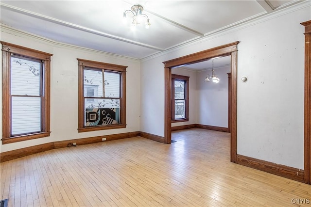 empty room featuring ornamental molding, light hardwood / wood-style flooring, and an inviting chandelier