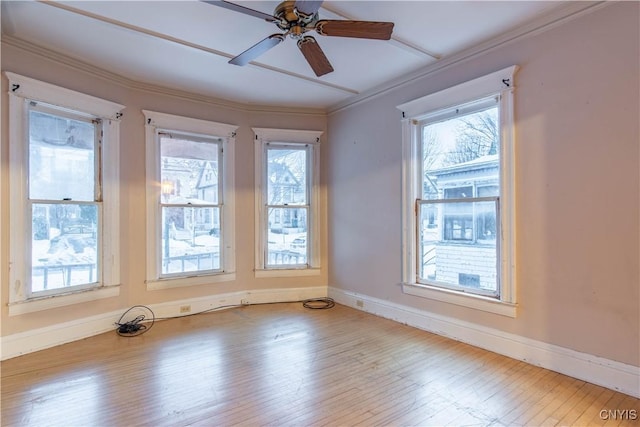 empty room with a wealth of natural light, ceiling fan, and hardwood / wood-style flooring