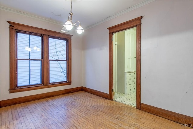 spare room featuring light wood-type flooring, crown molding, and a notable chandelier