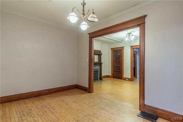 unfurnished room featuring a notable chandelier, light hardwood / wood-style floors, and ornamental molding