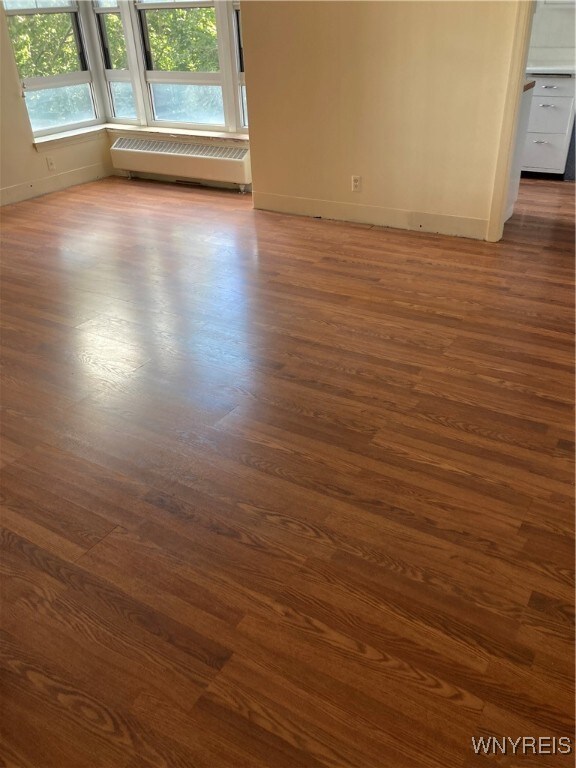 empty room with radiator and dark hardwood / wood-style floors