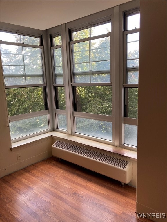 unfurnished sunroom with a baseboard heating unit and a healthy amount of sunlight