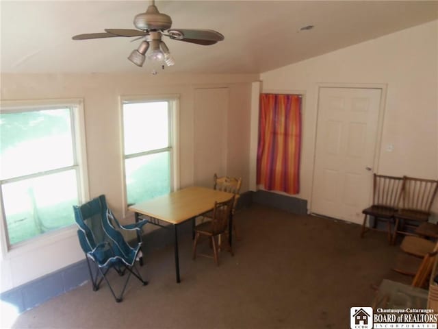 carpeted dining space with vaulted ceiling and ceiling fan