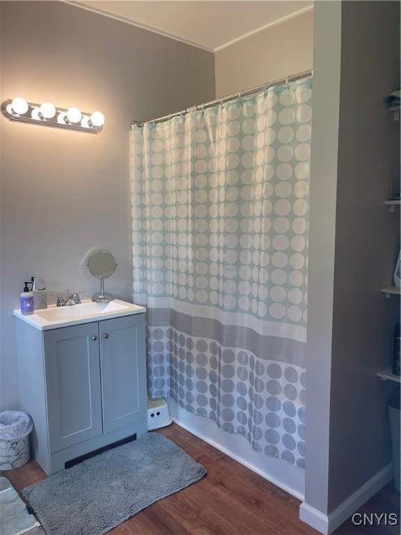 bathroom featuring hardwood / wood-style floors, shower / bathtub combination with curtain, and sink