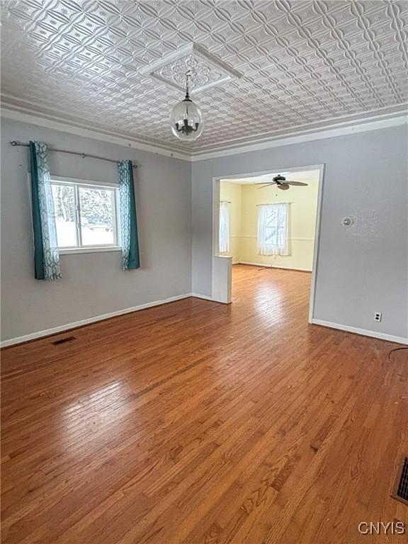 empty room featuring hardwood / wood-style floors, ceiling fan, and ornamental molding