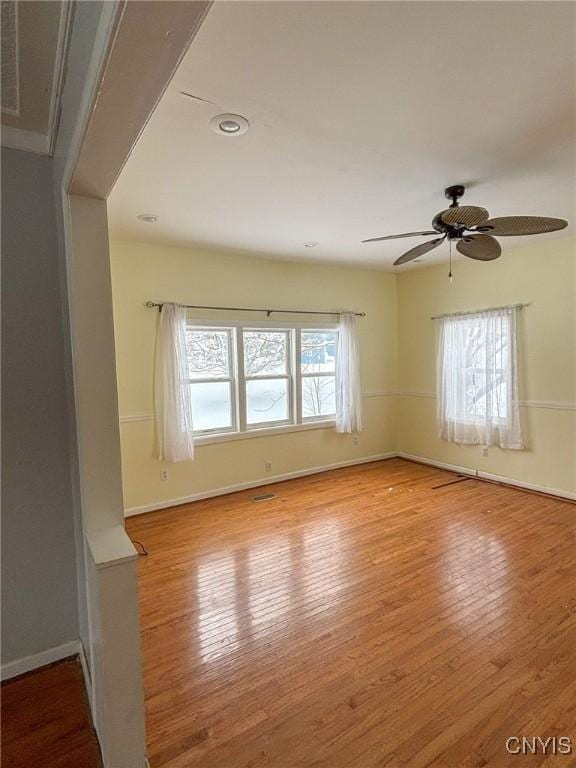 empty room with ceiling fan, a healthy amount of sunlight, and light hardwood / wood-style flooring